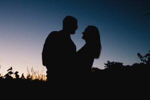 Silhouette of a couple sharing a tender moment outdoors during sunset.